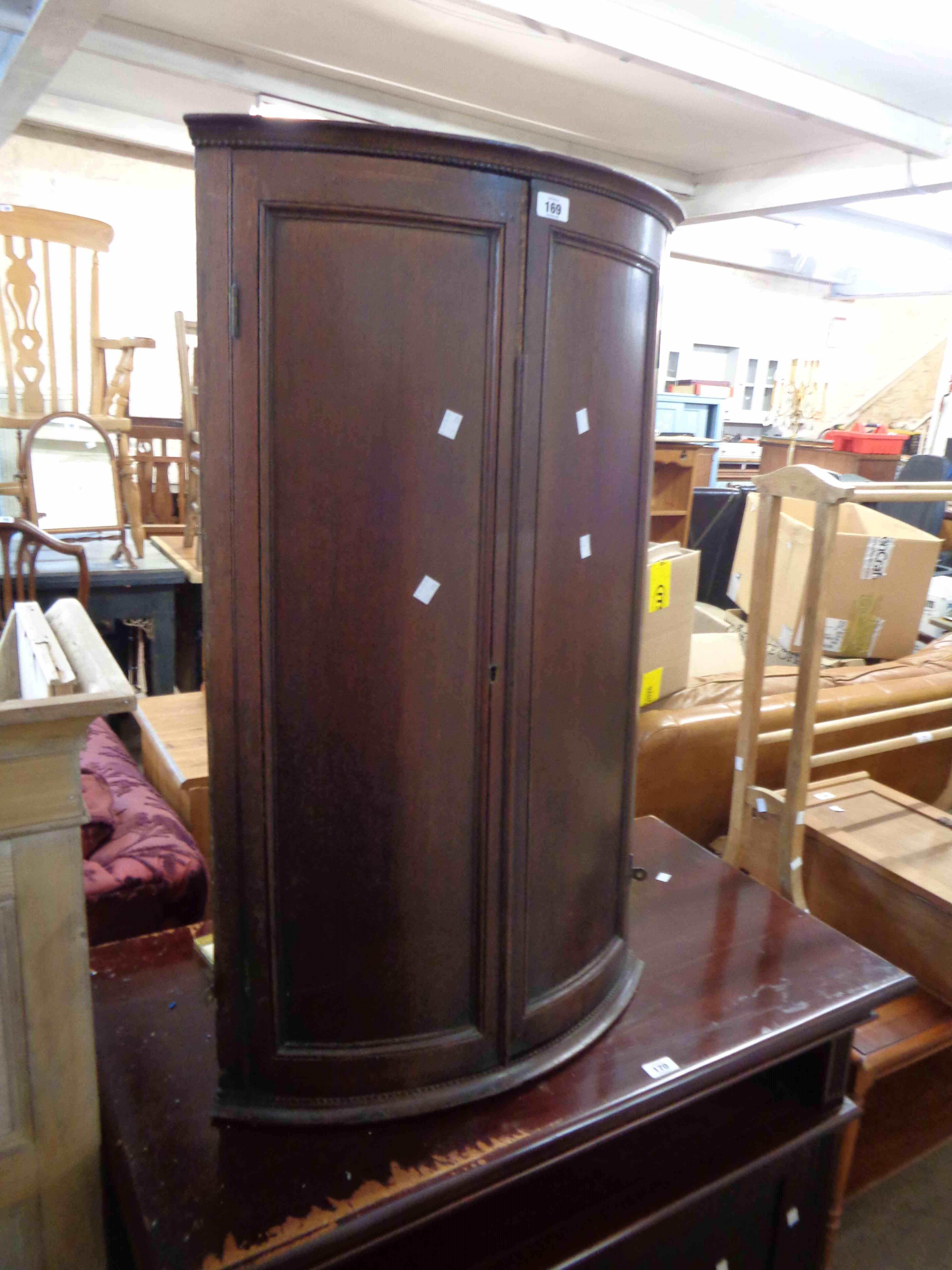 A 59cm 19th Century oak bow front corner cabinet with shelves enclosed by a pair of panelled