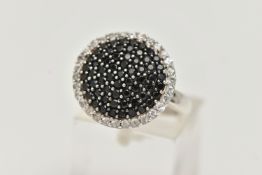 A GEM SET CLUSTER RING, comprised of black circular cut stones, pave set with a surround of