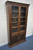 A LARGE PINE BOOKCASE, the two glazed doors enclosing four adjustable shelves, above two cupboard