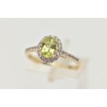 A 9CT GOLD PERIDOT AND DIAMOND RING, an oval cut peridot, set with a surround of round brilliant cut