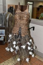 AN AUTUMNUL WICKER DISPLAY MANNEQUIN, on a rustic wooden stand, wicker bodice and tree branch and