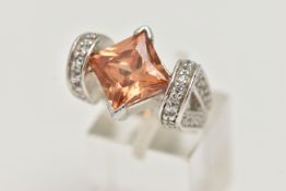 A WHITE METAL DRESS RING, principally set with a large square cut orange cubic zirconia, leading