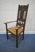 AN ARTS AND CRAFTS OAK RUSH SEATED ARMCHAIR, the back rest depicting a cottage under a tree,
