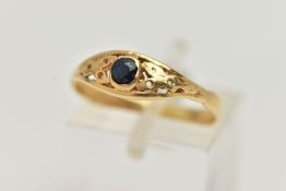 A YELLOW METAL SAPPHIRE RING, set with a single circular cut dark blue sapphire, open work surround,