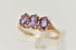 A 9CT GOLD AMETHYST RING, set with three oval cut amethysts, each claw set to the bifurcated