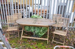 A MODERN TEAK GARDEN TABLE, 150cm long four matching folding chairs, a parasol base and a cover (7)