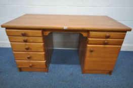 A HEAVY PINE EFFECT KNEE HOLE DESK, fitted with an arrangement of seven drawers and a single