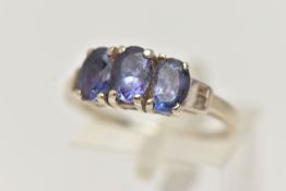 A 9CT GOLD GEMSET RING, three oval cut tanzanite, prong set in white gold leading on to baguette cut