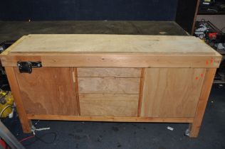 A BESPOKE PINE WORK BENCH with three graduated central drawers flanked by two cupboard doors, a vice