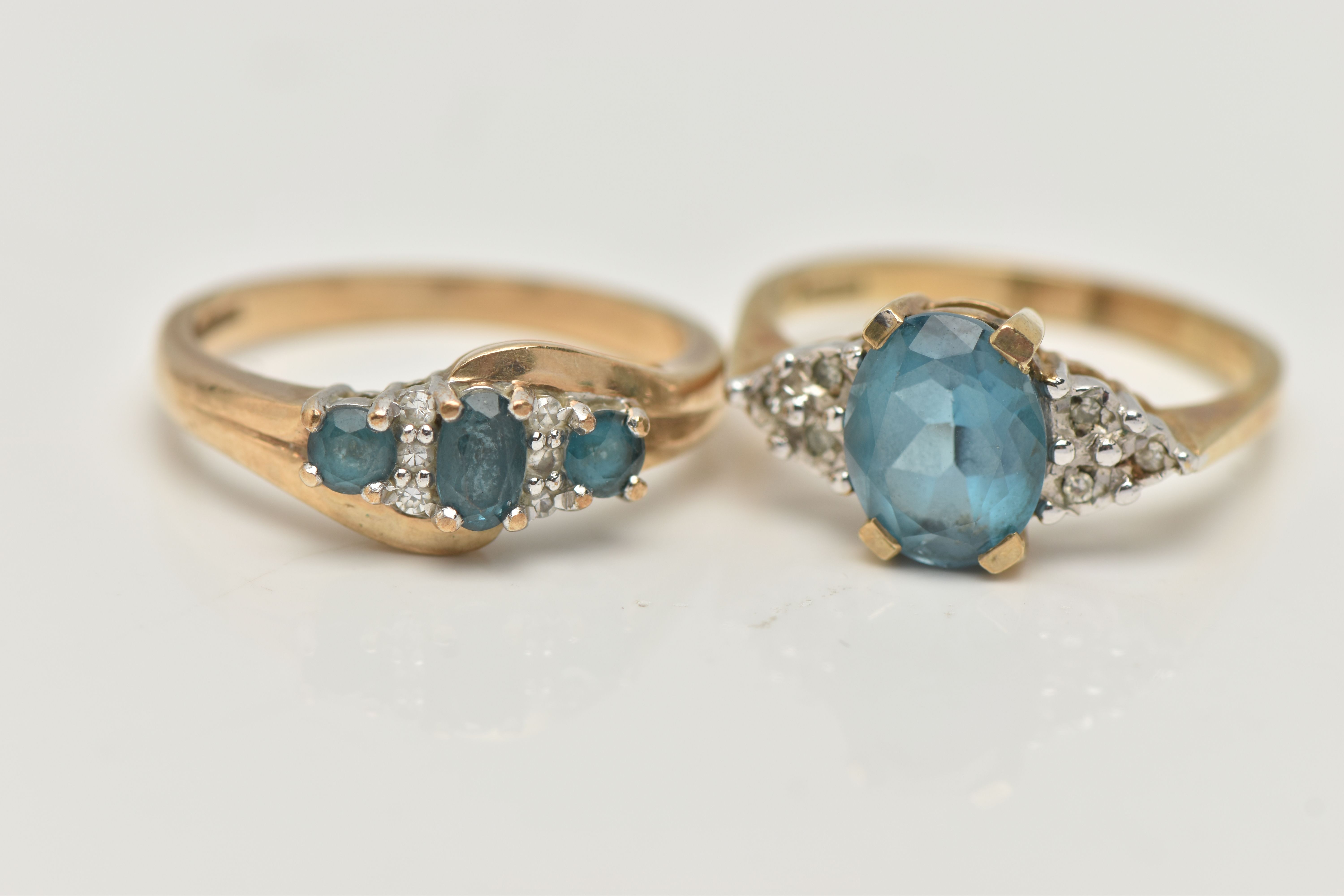 TWO 9CT GOLD GEM SET RINGS, the first an oval cut blue topaz, flanked with six single cut
