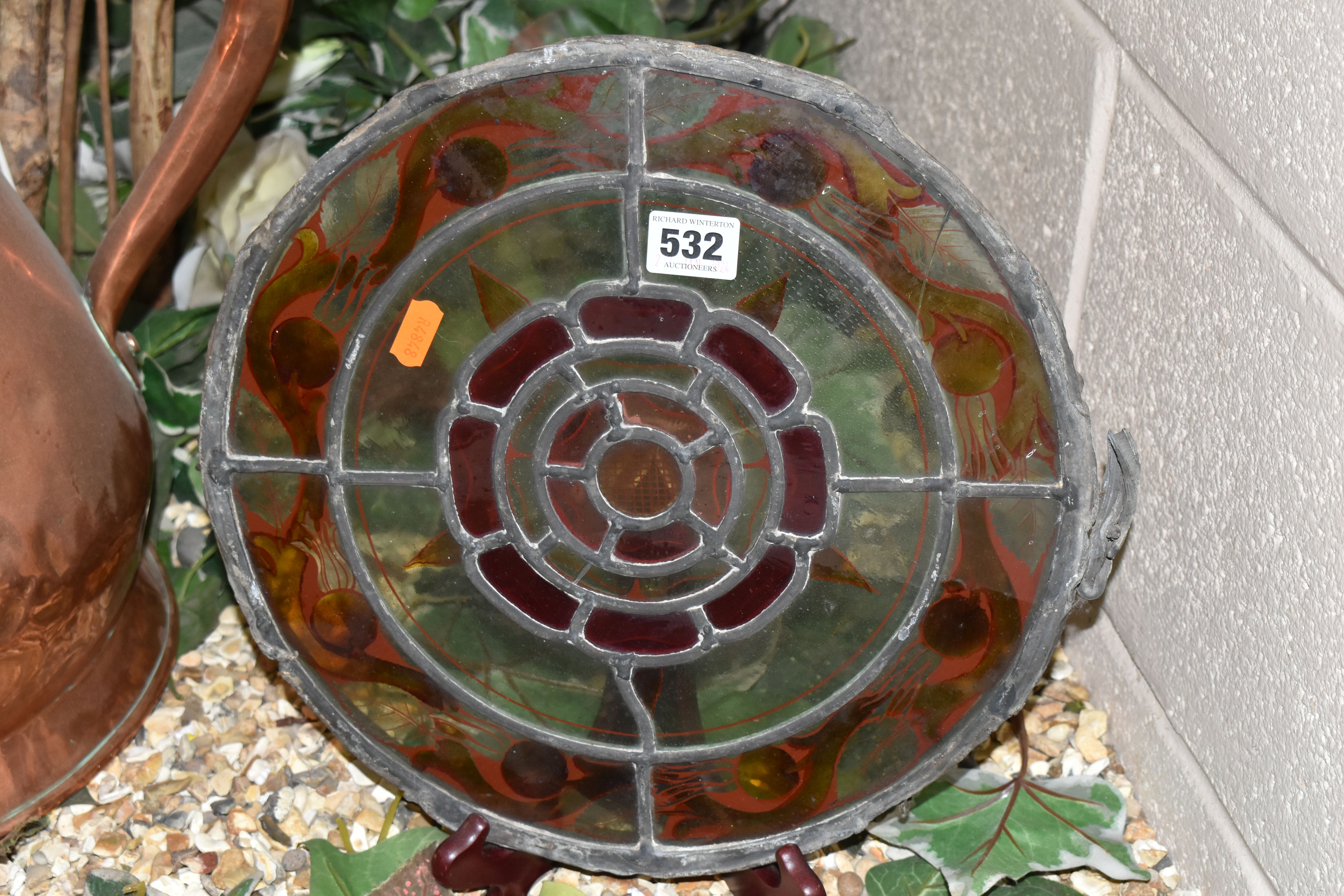 A CIRCULAR STAINED GLASS PANEL, on a metal frame, decorated with a central Tudor rose motif,