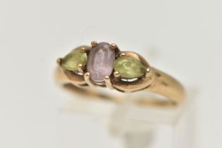 A 9CT GOLD GEM SET RING, an oval cut amethyst accompanied with two pear cut peridots, prong set in
