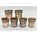 A SET OF SIX WHITE METAL SHOT GLASSES, each with an embossed leaf design with gilt interior, each