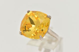 A DRESS RING, designed as a large yellow gemstone assessed as quartz, within a four claw setting,