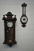 A WALNUT CASED VIENNA WALL CLOCK, with twin finials and central mask, the glazed door enclosing 7