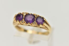 AN 18CT GOLD THREE STONE RING, three round cut amethysts, prong set in yellow gold, scrolling detail