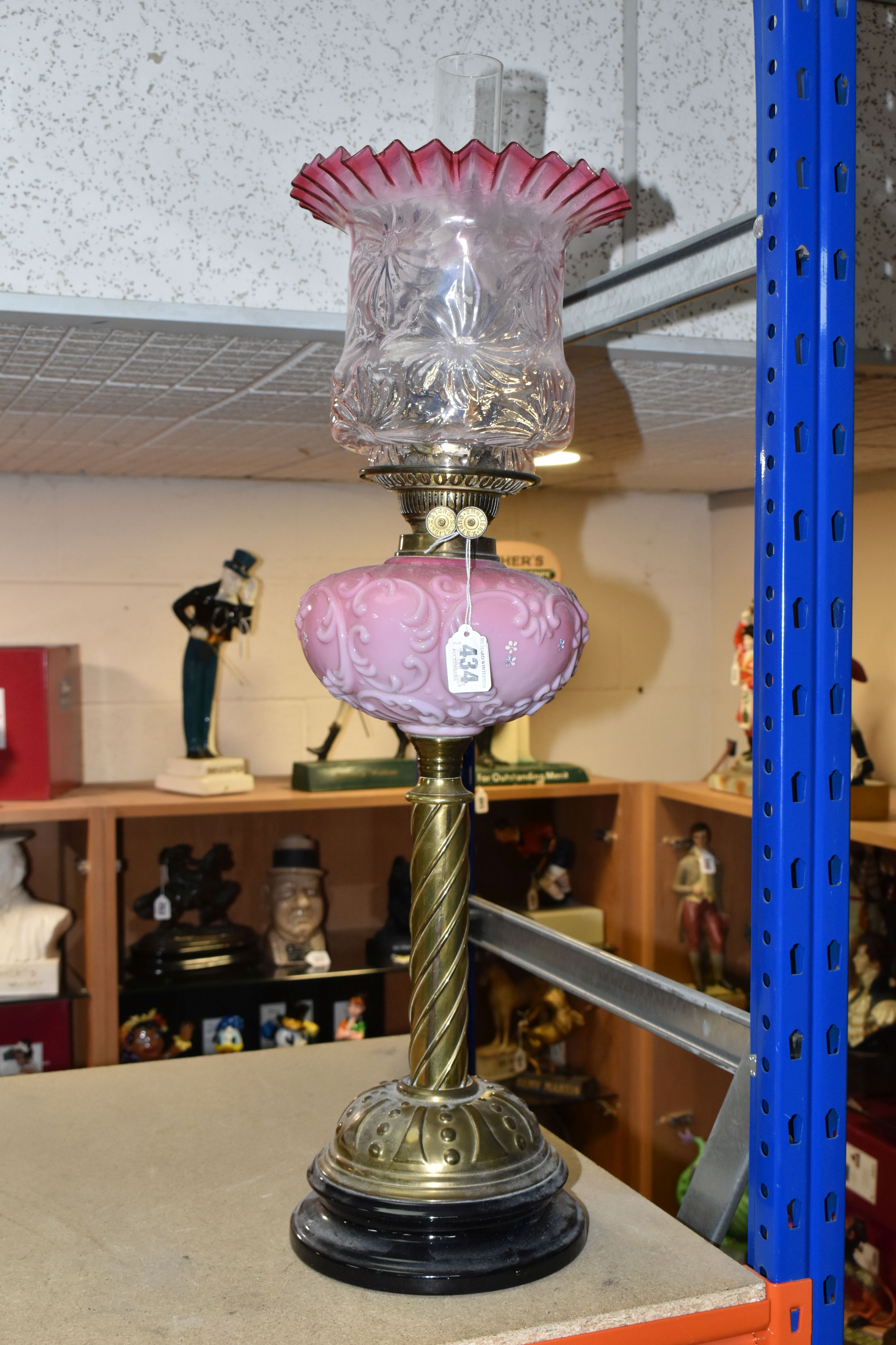 A TALL VICTORIAN BRASS OIL LAMP, with a pink glass reservoir, clear to cranberry frilled shade,