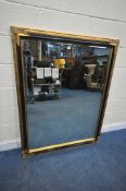 A RECTANGULAR GILT AND EBONISED FRAME BEVELLED EDGE WALL MIRROR, each corner with foliate detail,