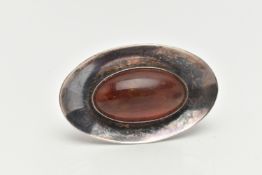A DANISH SILVER AND AMBER BROOCH, oval form concaved brooch, centrally set with an oval cabochon