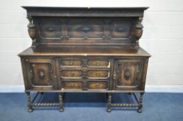 AN EARLY 20TH CENTURY OAK SIDEBOARD, the raised back with floral carving, geometric panels, on acorn