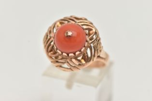 A YELLOW METAL CORAL RING, set with a raised coral cabochon with pin to the centre, in a claw