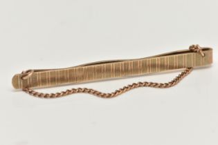 A 9CT GOLD TIE BAR, an engine turned pattern tie bar, fitted with a draping fine curb link chain,
