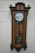 A 19TH CENTURY WALNUT VIENNA WALL CLOCK, with a shaped crest, flanked by two finials, the glass door