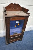 AN EARLY 20TH CENTURY OAK SMOKERS CABINET, the bevelled glass door enclosing a painted fitted