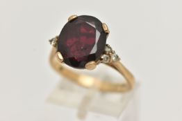 A 9CT GOLD GARNET RING, a large oval cut garnet, approximate length 13mm, flanked with six