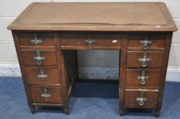 AN EARLY 20TH CENTURY OAK KNEE HOLE DESK, with a tan leather writing surface, fitted with nine