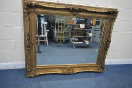 A LARGE RECTANGULAR GILT FRAME BEVELED EDGE WALL MIRROR, with scrolled and foliate carved detail,