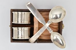 A CASED PAIR OF SILVER NAPKIN RINGS AND TWO SPOONS, engine turned pattern napkin rings with engraved