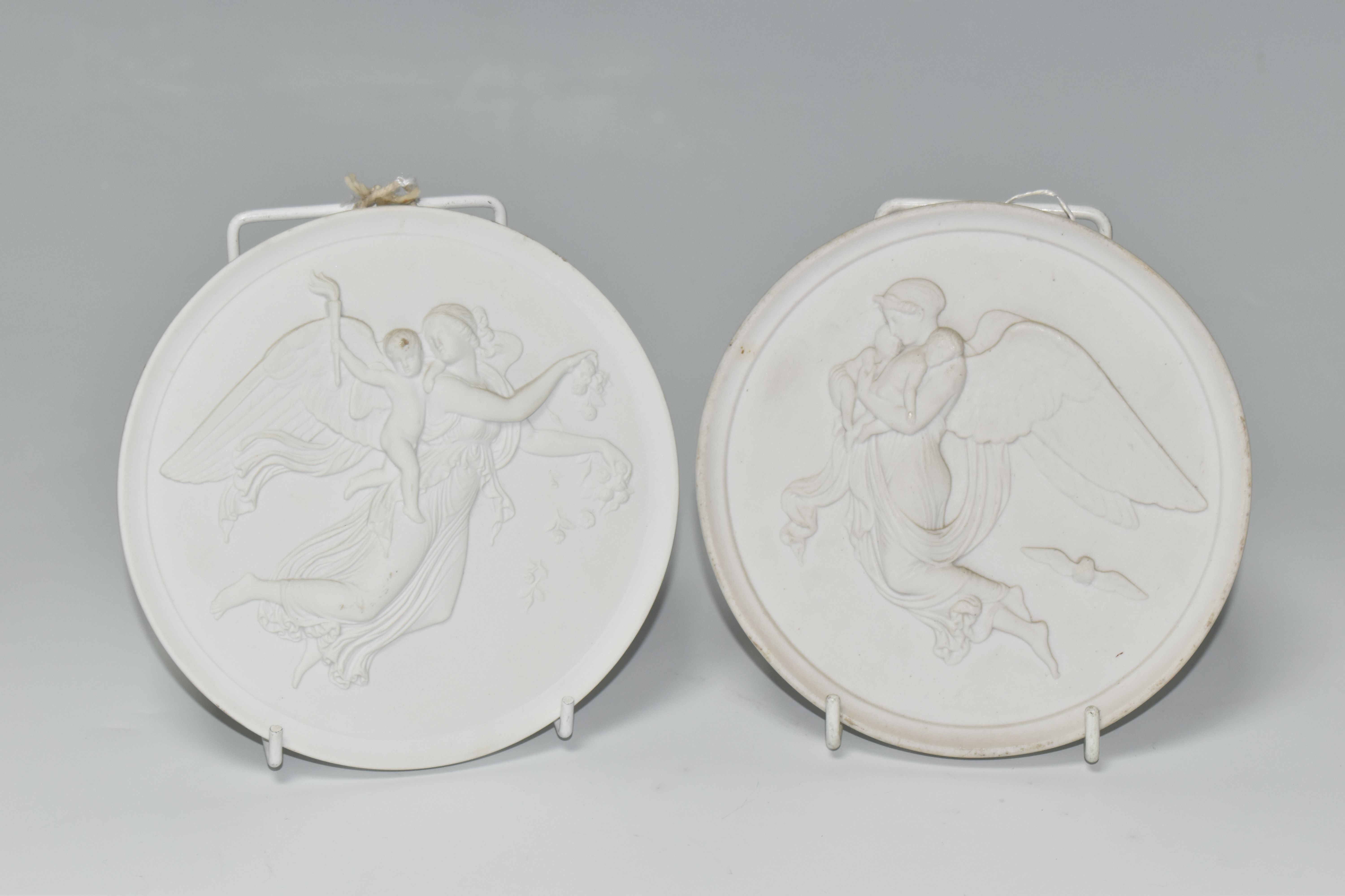 TWO ROYAL COPENHAGEN CIRCULAR BISQUE PLAQUES, depicting angels and cherubs, one bearing painted