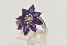 AN AMETHYST FLOWER RING, designed as amethyst petals to the cross over design shoulders, stamped