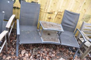 A MODERN METAL FRAMED CURVED GARDEN BENCH with raised two tier centre table and parasol holes in