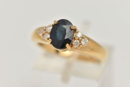 AN 18CT GOLD SAPPHIRE AND DIAMOND RING, the central oval sapphire flanked by three brilliant cut