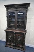 A LATE 19TH / EARLY 20TH CENTURY CARVED OAK GLAZED BOOKCASE, depicting lions masks and other detail,