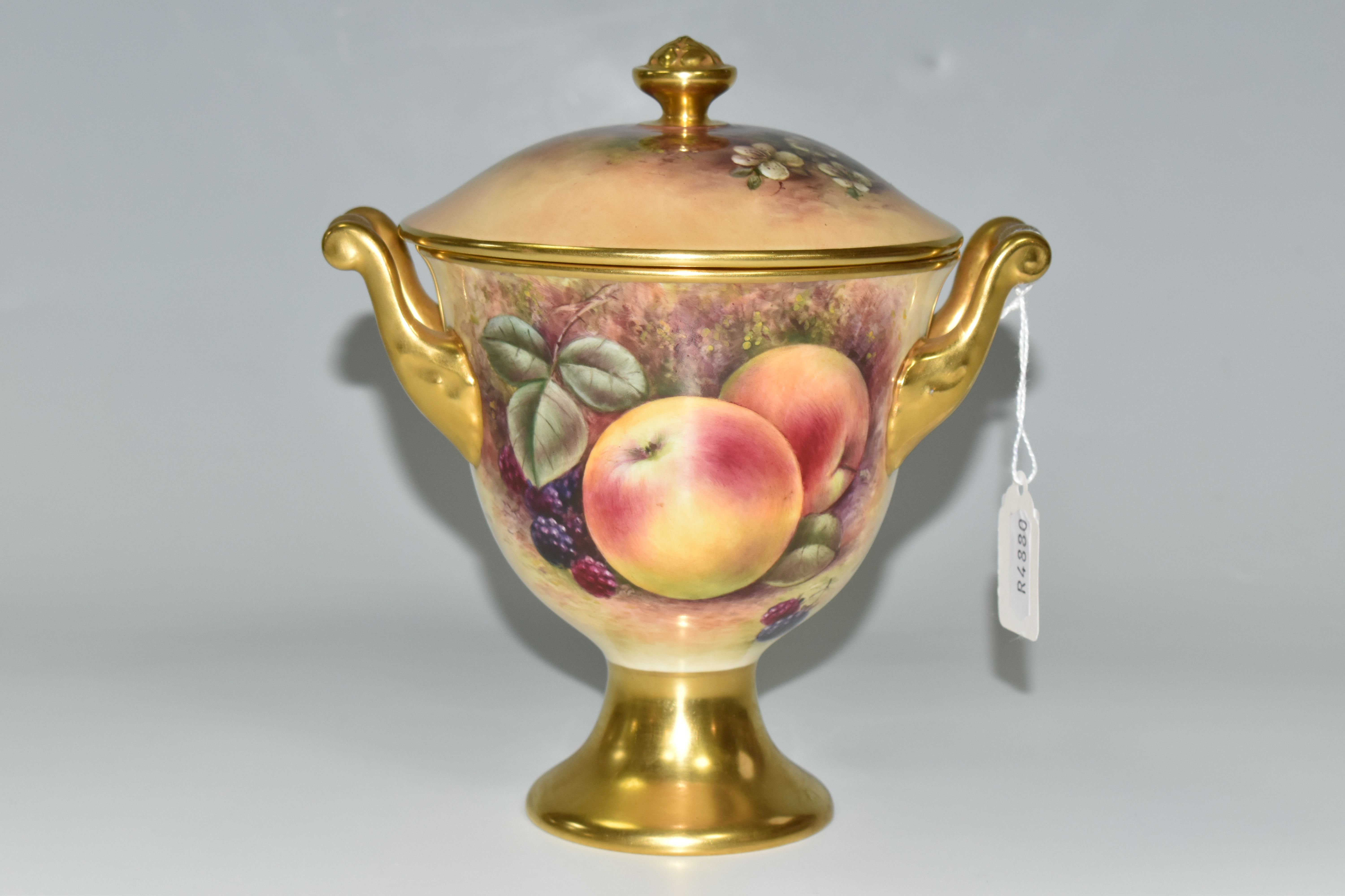 A COALPORT COVERED VASE, the gilt footed vase with twin gilt handles, hand painted with apples,
