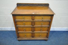 AN EARLY 20TH CENTURY OAK CHEST OF FOUR LONG GRADUATED DRAWERS, with a raised carved back, on bun