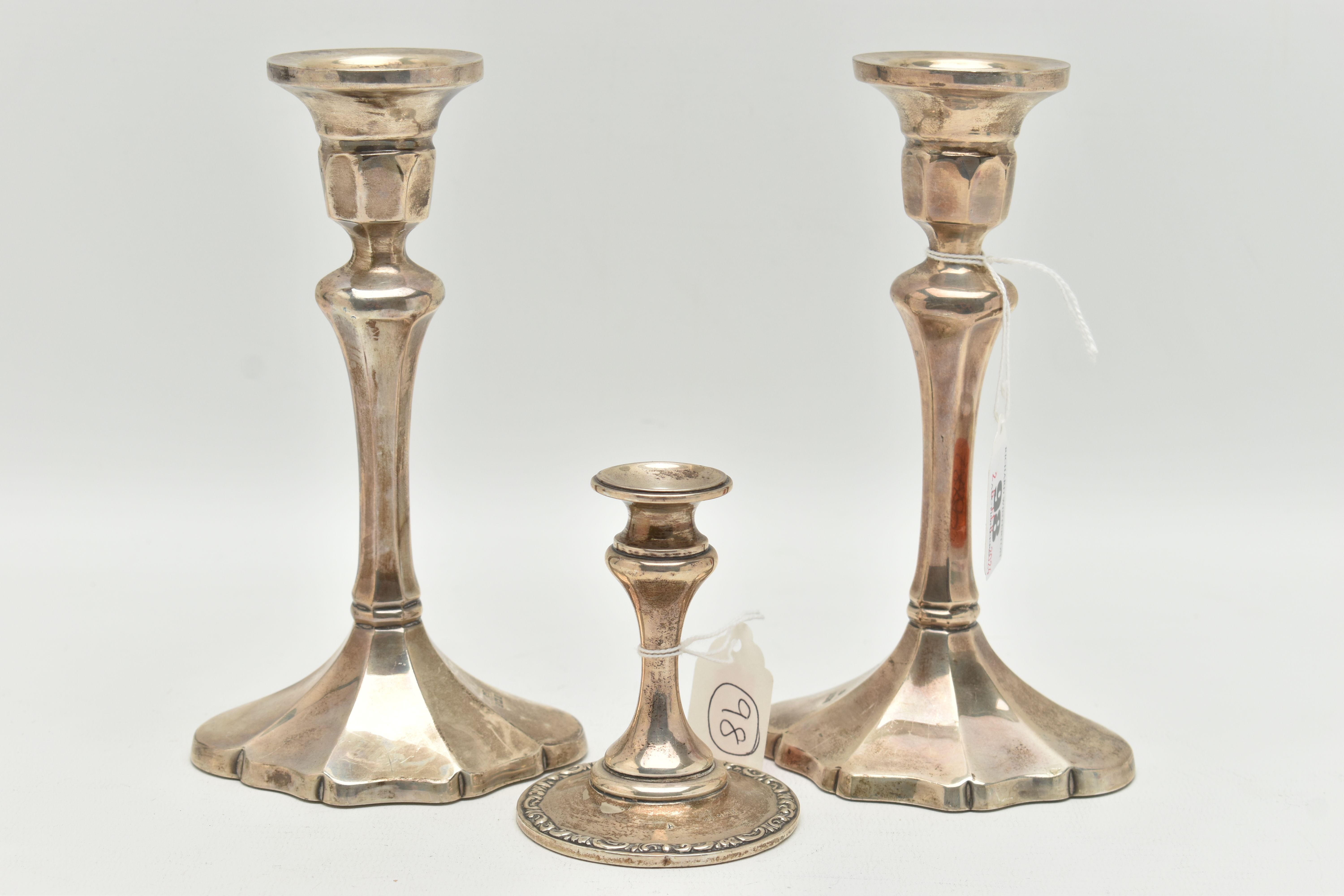 A PAIR OF ELIZABETH II SILVER CANDLESTICKS AND A DWARF CANDLE STICK, the first faceted pair of