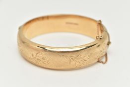 A 9CT GOLD HINGED BANGLE, a wide hollow bangle with etched floral detail, approximate width 16mm,