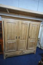A LARGE GOOD QUALITY LIGHT OAK TRIPLE DOOR WARDROBE, with a fixed cornice, an arrangement of