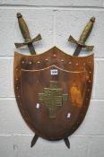 A DECORATIVE HANGING COPPER SHIELD, with brass trim and coat of arms, cross swords to rear, width
