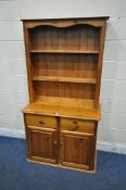 A MODERN PINE DRESSER, the two tier plate rack, atop a base with two drawers and two cupboard doors,