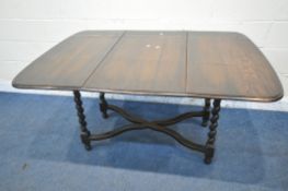 A 20TH CENTURY STAINED ELM REVOLVING DROP LEAF DINING TABLE, raised on barley twist supports, united