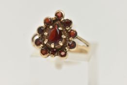 A 9CT GOLD GARNET CLUSTER RING, designed as a central pear shape garnet within a circular cut garnet