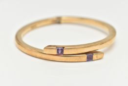 A 9CT GOLD AMETHYST BANGLE, the crossover bangle with sprung hinge, set to each terminal with a