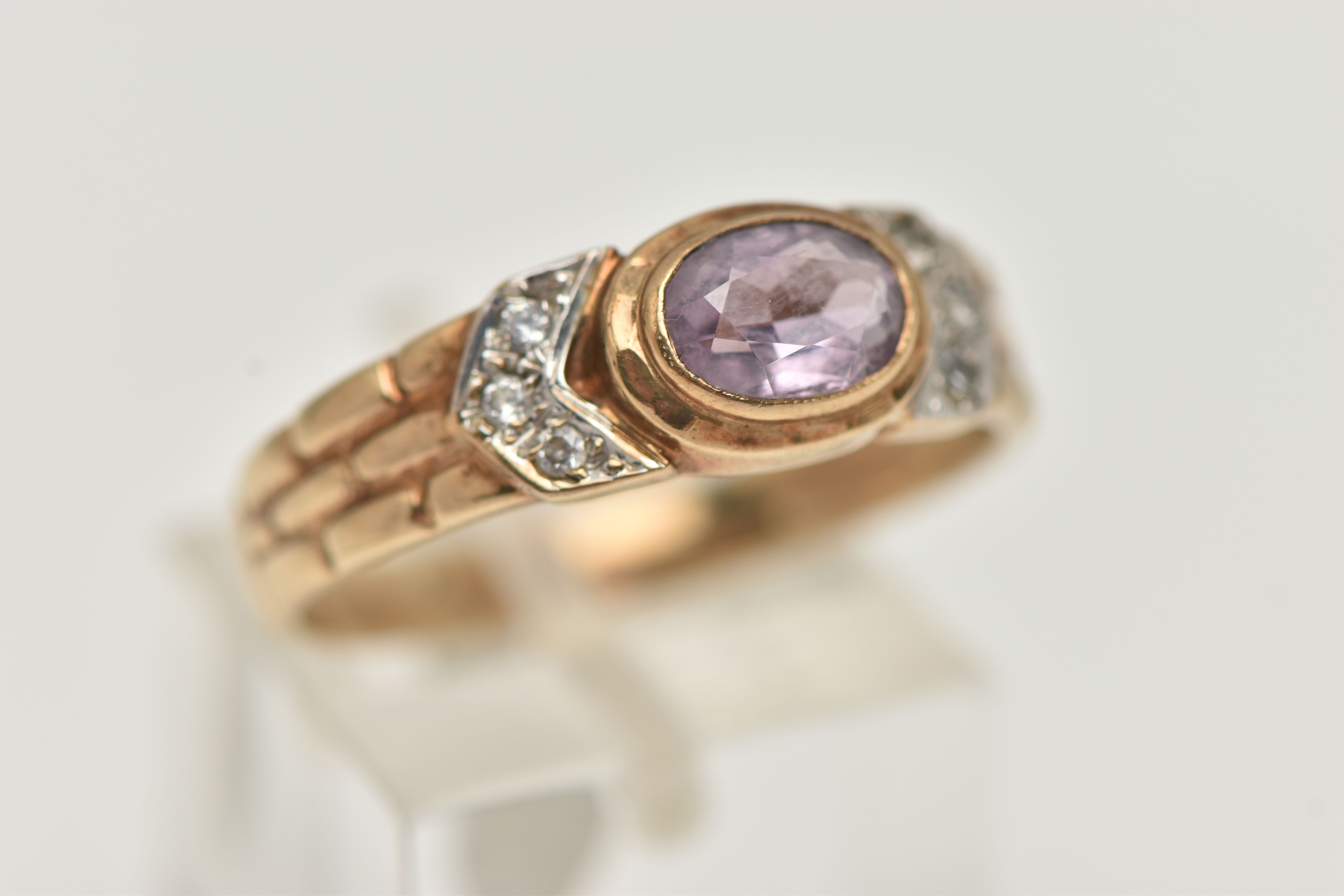 A 9CT GOLD AMETHYST RING, the central oval amethyst in a collet setting, flanked by colourless - Image 4 of 4