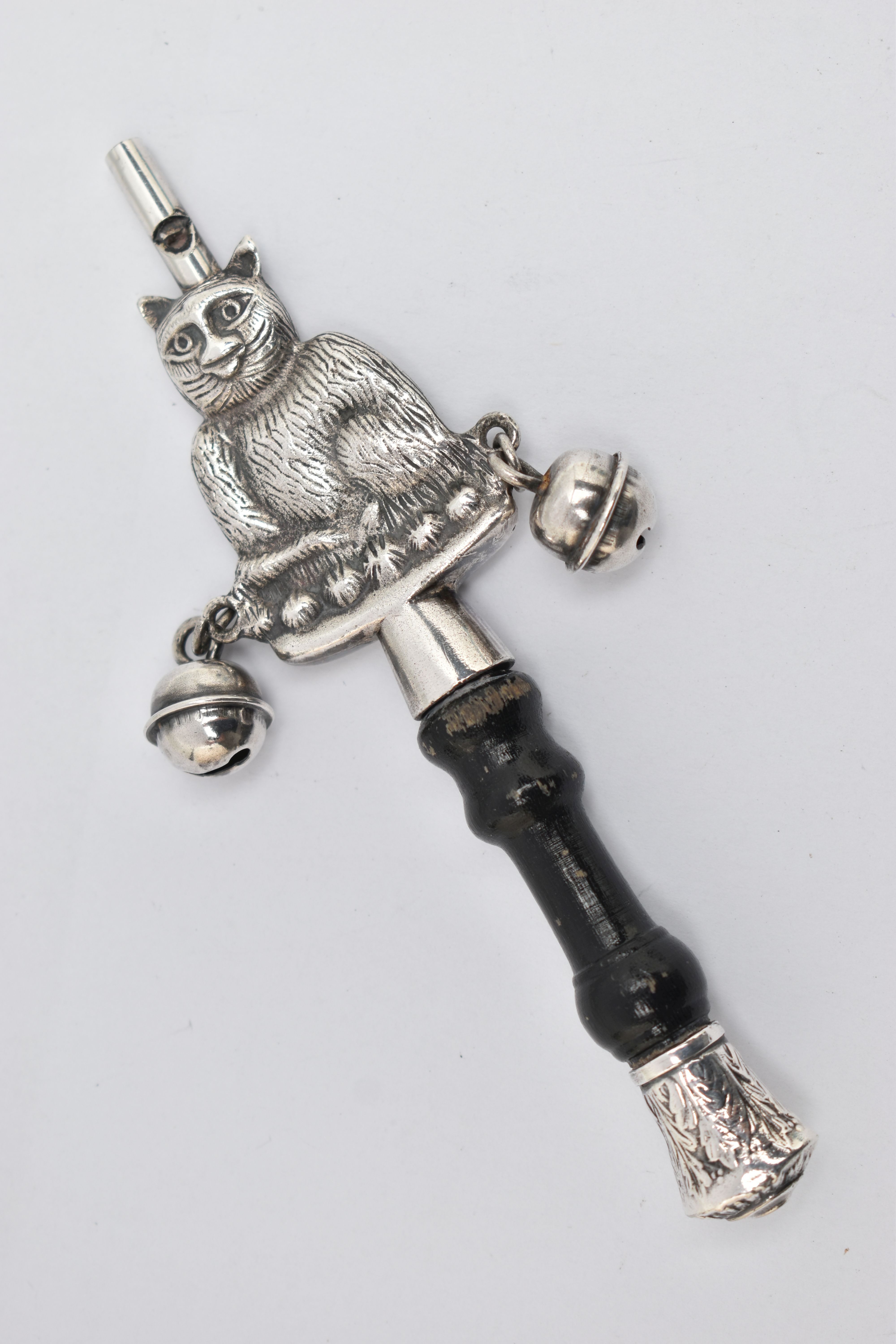 A WHITE METAL BABY RATTLE, in the form of a cat, fitted with two bells either side and a whistle