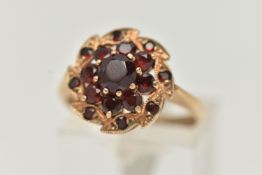 A 9CT GOLD GARNET CLUSTER RING, designed as a circular garnet cluster, with leaf shape surround